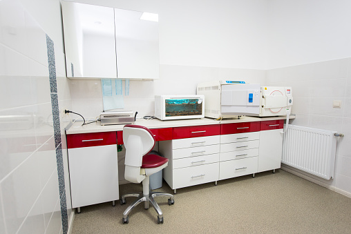 Modern dental laboratory equipment in red and white, steam sterilizer