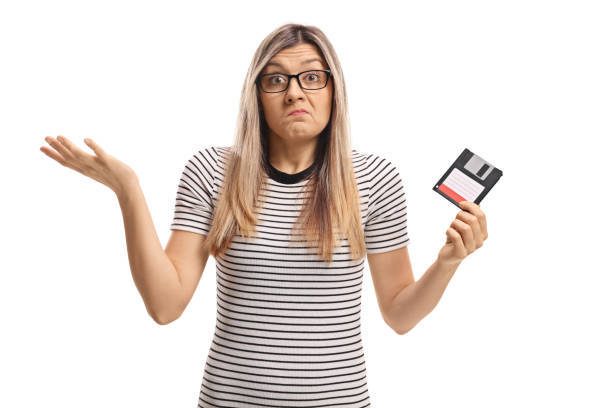 istock Confused young woman holding a floppy disk 899666588