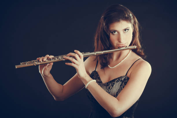istock Woman playing transverse flute on black. 899670820