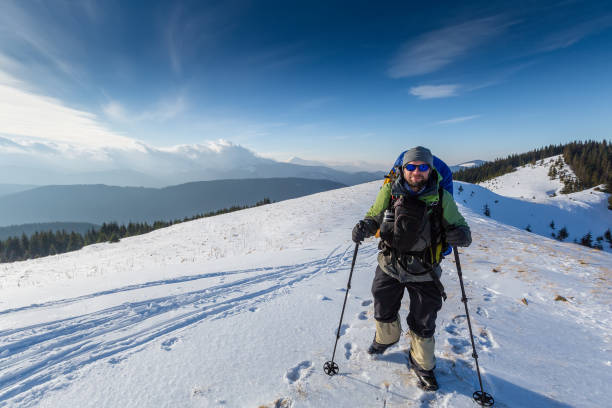 Hiker is posing to the camera in winter mountains