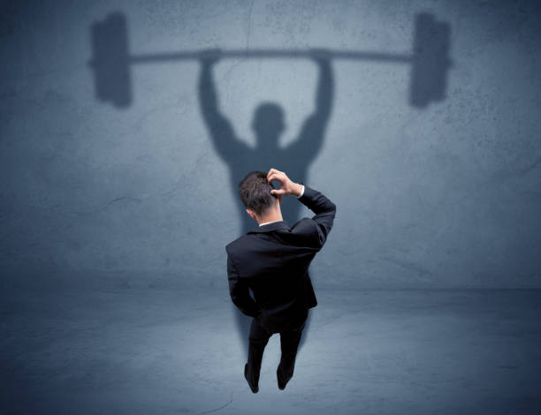 istock Businessman with weight lifting shadow 899683734