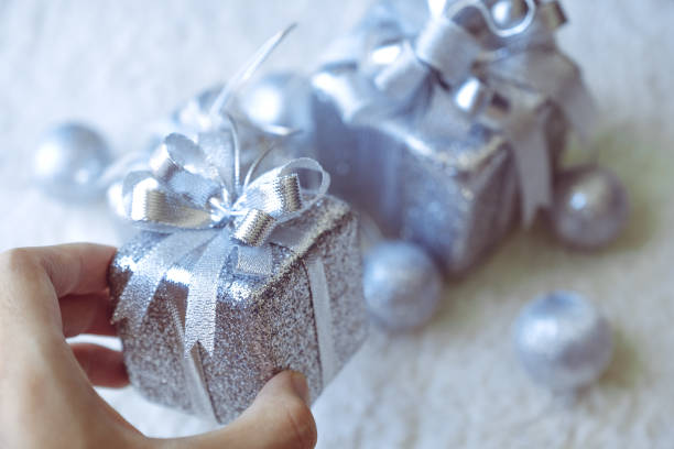 istock Top view image of a hand holding golden present boxes and Christmas decorations on white carpet background 899690712