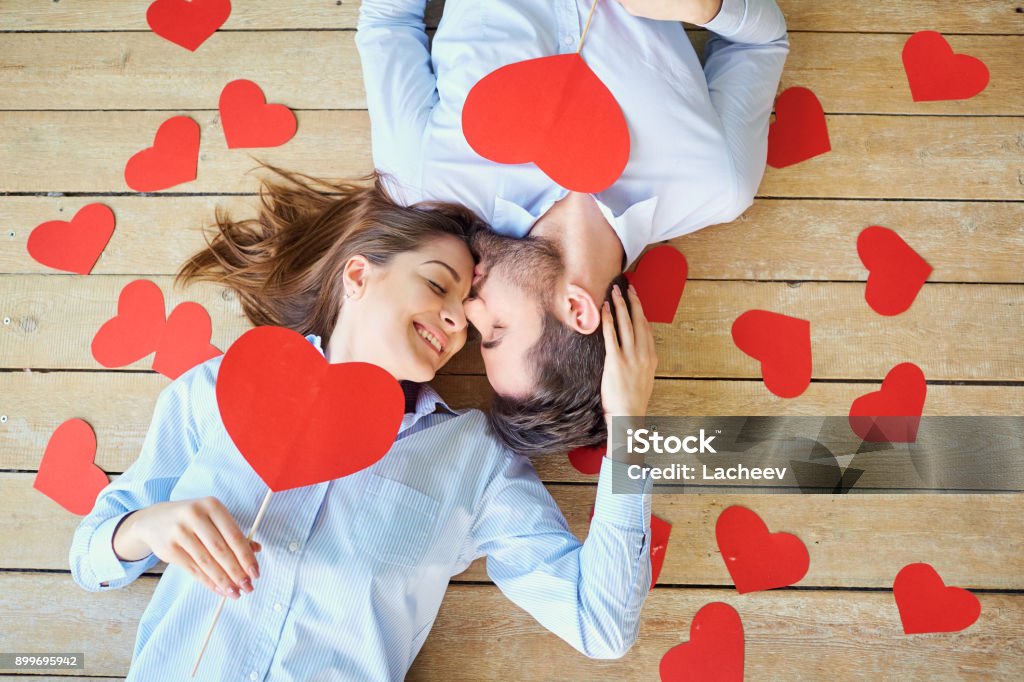 Couple lying on the wooden floor with hearts view from above Couple lying on the wooden floor with hearts view from above. Valentine's Day. Falling in Love Stock Photo