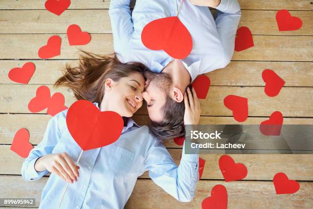 Couple Lying On The Wooden Floor With Hearts View From Above Stock Photo - Download Image Now