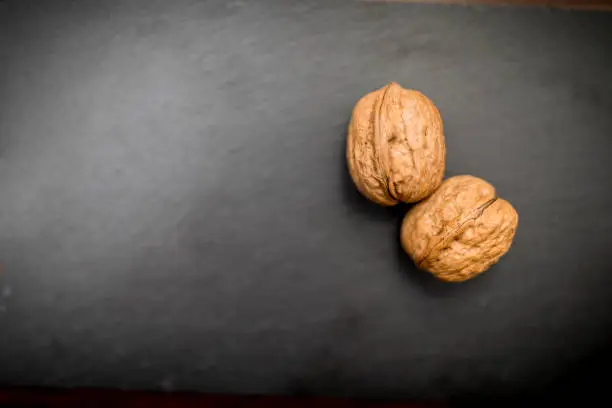 Close up of two walnuts on a black slate background, testicle concept could be used for a testicular cancer advert