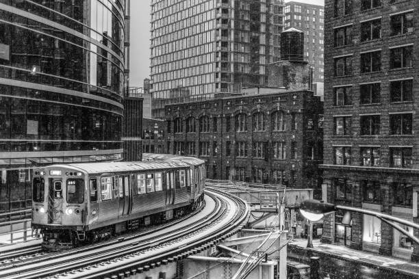Subway train wrapping around snow covered curved track Subway train wrapping around snow covered curved track with skyscrapers train station black and white stock pictures, royalty-free photos & images