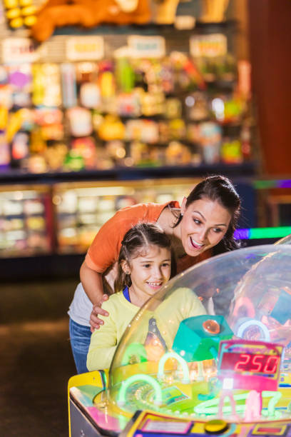 istock Mother and daughter playing game in amusement arcade 899712526