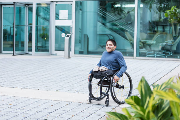 istock Young man in wheelchair on city sidewalk 899712898