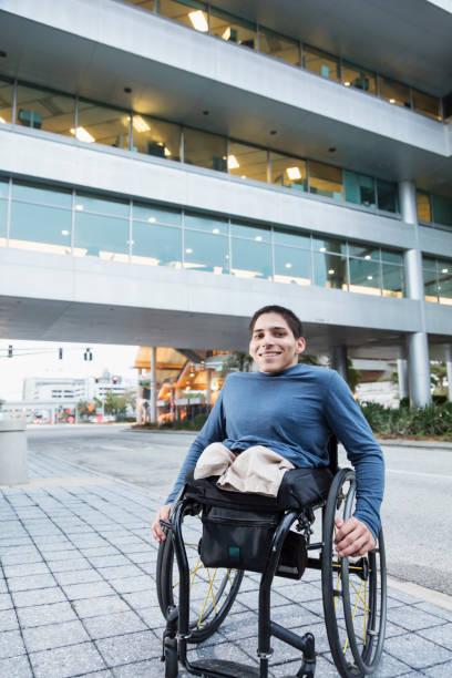 istock Young man in wheelchair on city sidewalk 899712902
