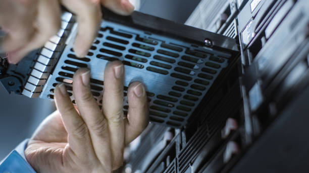 low angle shot in fully working data center it engineer installs hard drive into server rack. detailed and technically accurate footage. - network server rack data center in a row imagens e fotografias de stock