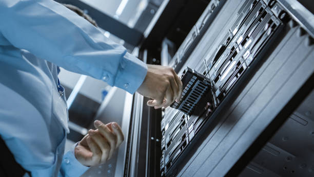 long angle shot in fully working data center it engineer installs hard drive into server rack. detailed and technically accurate footage. - network server rack data center in a row imagens e fotografias de stock