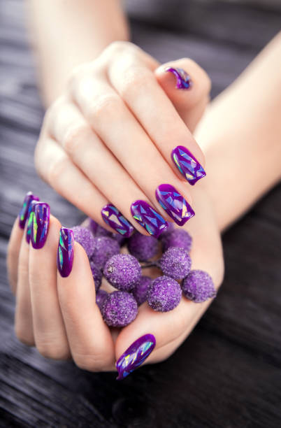 istock Shattered glass purple manicure on black background 899732452