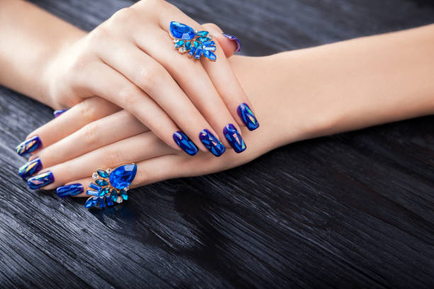 istock Shattered glass blue manicure on black background 899732474