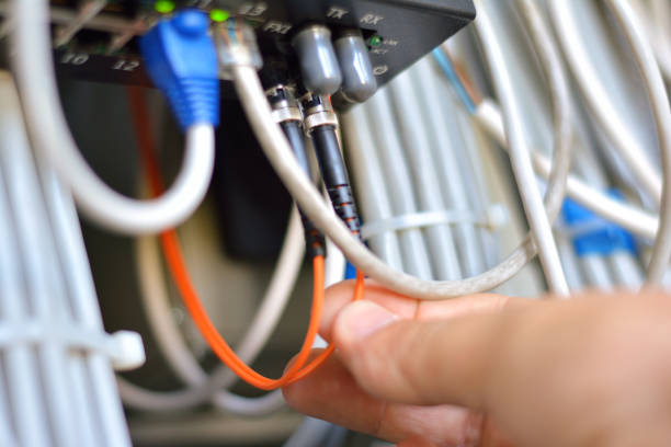 Man inserting fiber optic cable to the switch Hand with fiber optic cables connected to servers. Network engineer insert patch cord computer network router communication internet stock pictures, royalty-free photos & images