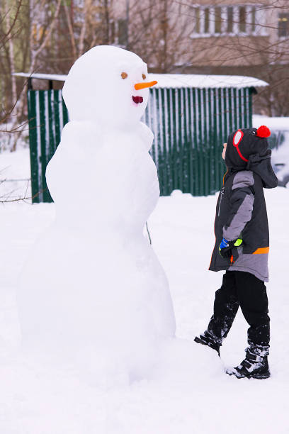 istock snowman in the winter  and a boy 899739350