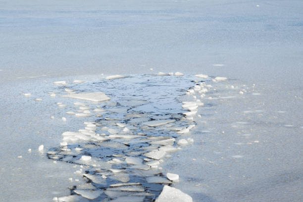 Hole in the thin ice. Someone fell through the ice. Dangerous concept. Freezing and melting time for ice on the water reservoirs in winter. stock photo
