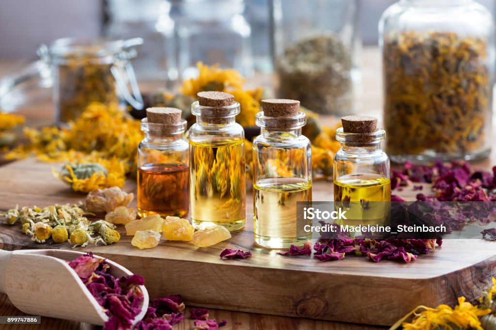 Botellas de aceite esencial de manzanilla, caléndula, pétalos de rosa secos e incienso - Foto de stock de Aromaterapia libre de derechos