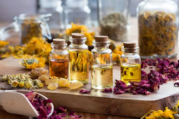 Photo of Bottles of essential oil with dried rose petals, chamomile, calendula and frankincense