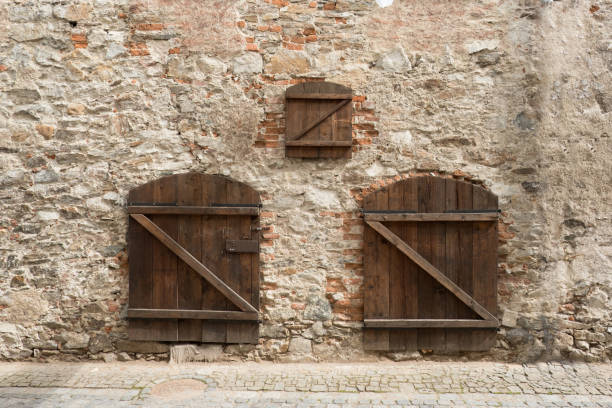 istock Medieval brick wall with two wooden doors and a small window, covered up with wood. Old brick wall background texture. Stone wall in a small medieval town on Cesky Krumlov, Czech Republic. 899748108