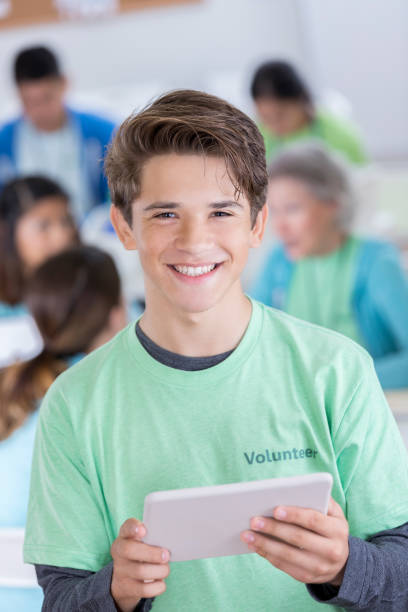 крупным планом испаноязычных подростков мальчик добровольцев улыбается для камеры - community outreach child social worker waist up стоковые фото и изображения