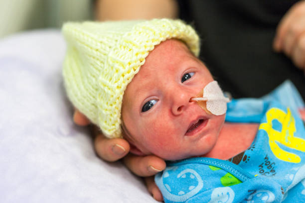 Premature baby in the neonatal intensive care unit with eyes open. stock photo