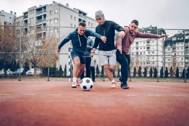 Four people playing football in schoolyard