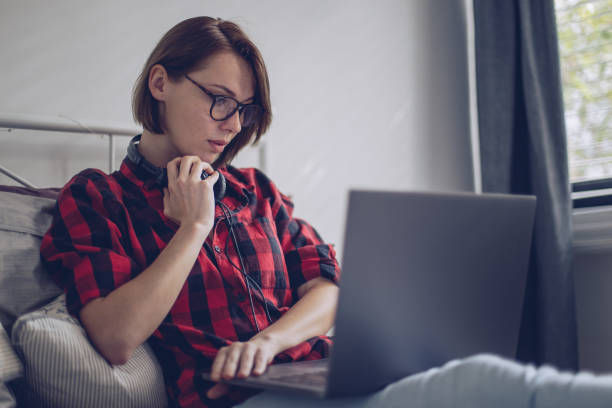 istock Beautiful young woman using her laptop in the bed 899800946