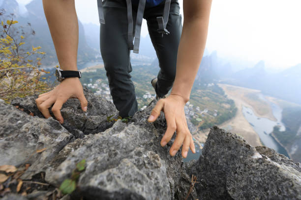 istock brave woman backpacker climbing rock at mountain top cliff edge 899816026