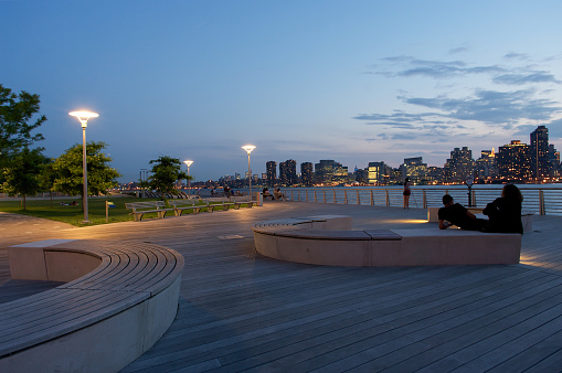 Long Island City, New York. June 16, 2011 - Two guys sitting on the bench facing the skyline of New York.