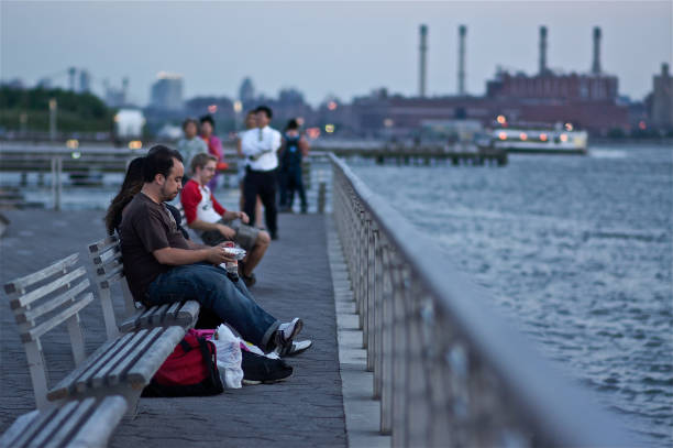 Long Island City, New York. June 16, 2011 - People sitting on the bench facing the skyline of New York.