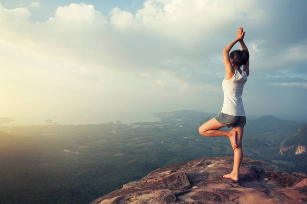 istock one woman practicing yoga at mountain peak cliff edge 899828444