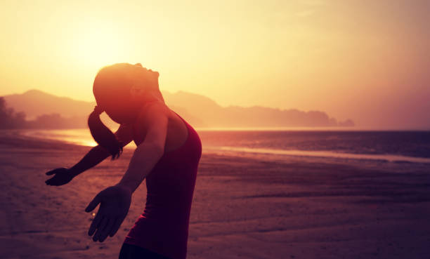 istock Cheering young woman with open arms on sunrise beach 899828914