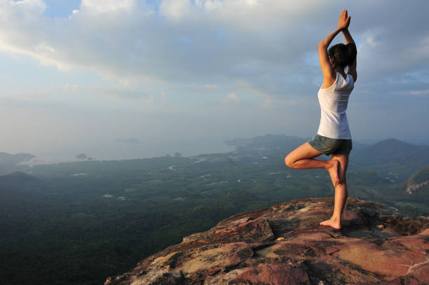 istock one woman practicing yoga at mountain peak cliff edge 899828958