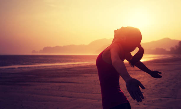 istock Cheering young woman with open arms on sunrise beach 899829134