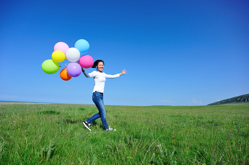 young asian woman with balloons on green grassland