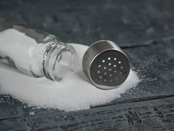 istock White salt poured from the open salt shaker on wooden table. 899832666
