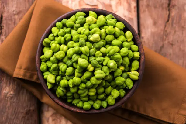 Fresh Green Chickpeas or Chick peas also known as harbara or harbhara in hindi and Cicer is scientific name, served in a wooden bowl or plate. selective focus