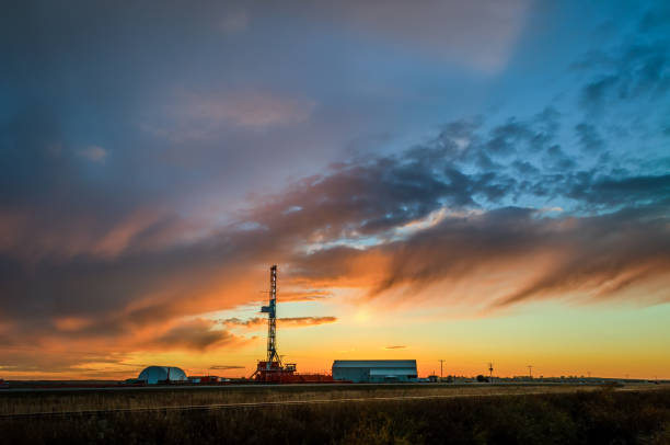 plataforma de petróleo no campo ao entardecer com céu nublado incrível, perto da estrada de ferro em horário de verão - oil pumping unit at sunset time - fotografias e filmes do acervo