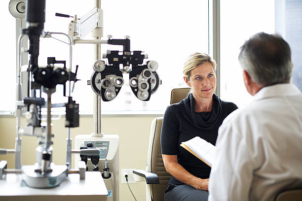 une femme à l'écoute de son opthamologist - examen ophtalmologique photos et images de collection