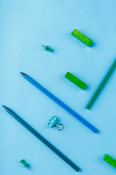 istock Several pencils, clips and crayons, green and blue, on a blue background. View from above. 899882308