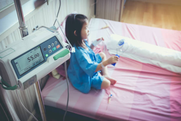 istock Illness asian child admitted with saline iv drip on hand. 899882550