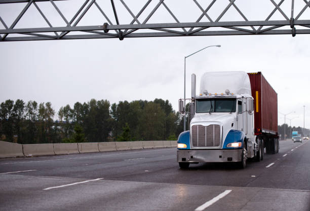istock Big rig semi truck with container on flat bed trailer running on raining highway 899884834