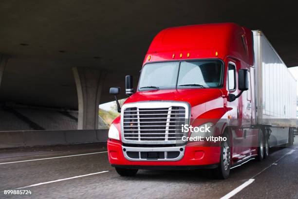 Bright Red Modern Big Rig Semi Truck With Dry Van Trailer Running Under Concrete Bridge Stock Photo - Download Image Now