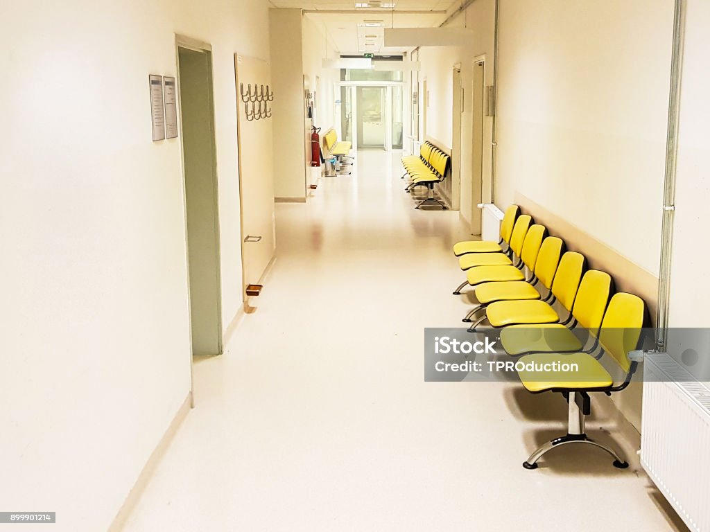 Empty seats in a hospital Empty yellow waiting seats in a hospital hallway Accidents and Disasters Stock Photo