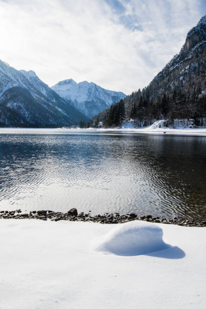 schönen winter verschneite landschaft reflexion über see lago del predil mit isolierten schneebedeckten felsen in den julischen alpen, italien - julian alps mountain lake reflection stock-fotos und bilder