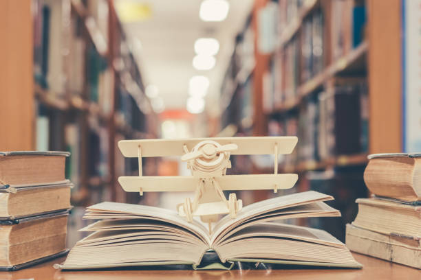 invención de la educación con el modelo de avión en libro abierto viejo en la biblioteca de la escuela - interés humano fotografías e imágenes de stock