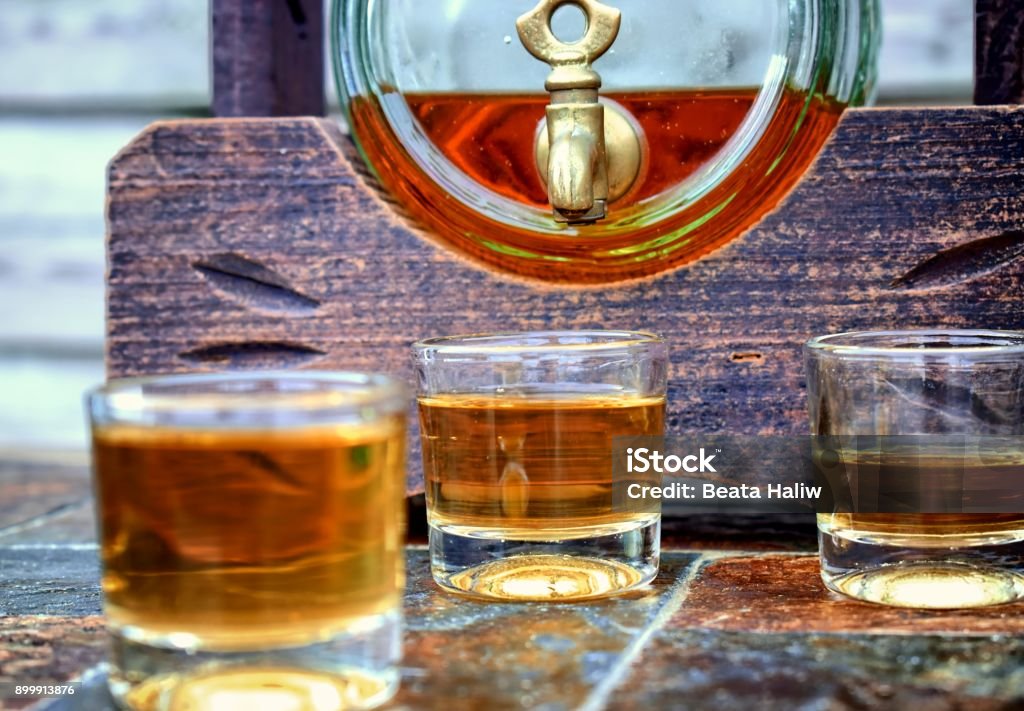 Alcohol,taste and drink concept. Glasses with whiskey,old glass barrel on stone table and wooden background. Alcohol - Drink Stock Photo