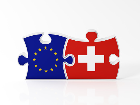 Jigsaw puzzle pieces textured with European Union and Swiss flags on white. Horizontal composition with copy space. Clipping path is included.