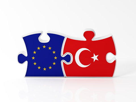 Jigsaw puzzle pieces textured with European Union and Turkish flags on white. Horizontal composition with copy space. Clipping path is included.