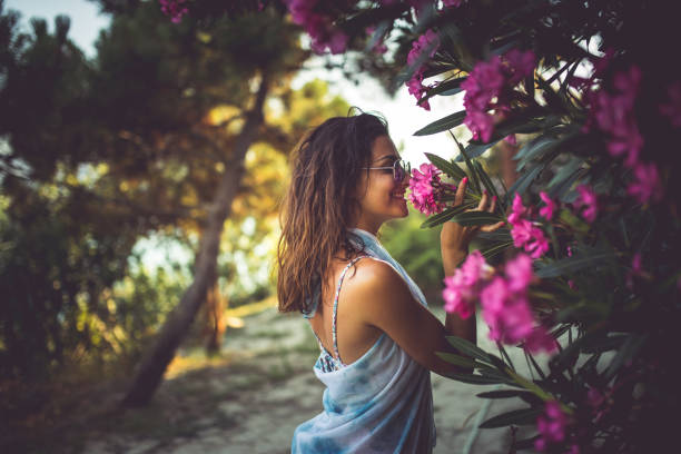 This smells nice Woman smelling tropical pink flowers zakynthos stock pictures, royalty-free photos & images